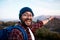 An excited backpacker points to the mountain view behind him on hiking trip