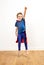 Excited beautiful little boy dressed like a powerful superhero jumping