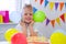 Excited Birthday boy with colorful balloons near birthday rainbow cake. Festivel background. Funny birthday party