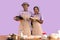 Excited black couple cooking together, holding homemade dough on violet studio background