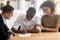 Excited black couple sign agreement at realtor office