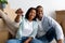 Excited black married couple showing home keys while sitting among cardboard boxes, selective focus