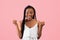 Excited black woman in summer dress gesturing YES on pink studio background