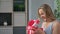 Excited blonde woman smiling opening red festive gift box with bow having positive emotion