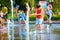 excited boy having fun between water splashes, in fountain. Summer in the city