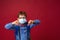 Excited boy in mask, glasses, with school backpack shows gesture of disapproval