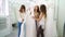 Excited bride with bridesmaids trying on stylish white dress in wedding salon