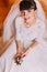 Excited bride in gorgeous white dress waiting for her wedding posing with cute floral boutonniere