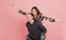 Excited cheerful young couple having fun while man piggybacking his girlfriend isolated over pink background