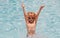 Excited child boy in sunglasses splashing in pool . Kid boy swim in swimming pool.