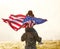 Excited child sitting with american flag on shoulders of father reunited with family