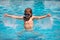 Excited child in sunglasses in pool in summer day. Child in summer swimming pool splashing in water having fun leisure