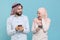 Excited couple friends arabian muslim man wonam in keffiyeh kafiya ring igal agal hijab clothes isolated on blue