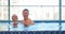 Excited couple laughs and hugs in swimming pool water
