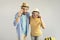 Excited couple looks surprised at the camera from under sunglasses standing on a gray background.