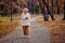 excited elderly female stand in autumn park looking at side, laughing outdoors