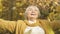 Excited elderly woman throwing yellow leaves, enjoying autumn nature in park