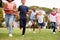 Excited Elementary School Pupils Running Across Field At Break Time