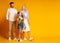 Excited Family Looking At Empty Space Standing Over Yellow Background