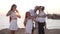 Excited family showing heart shape with hands looking at camera smiling standing on Mediterranean sea beach at golden