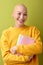 Excited female with bald head holding books in hands and smiling, enjoying education