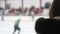 Excited female supporter watching hockey match, team players skating on ice rink