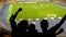 Excited football fans cheering team during soccer match at crowded stadium