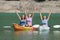 Excited friends celebrating raising arms in kayaks in a lake