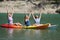 Excited friends celebrating vacation raising arms on kayaks