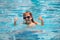 Excited funny kid with thumbs up in sunglasses in pool in summer day. Child in summer swimming pool.