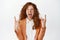 Excited ginger girl in business suit rocking, showing heavy metal horns and screaming, having fun, enjoying something