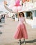 Excited girl with balloons in pink prom dresses at amusement park. Teenagers in pink evening dresses on vacation.