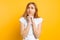 The excited girl is frightened by something, bites her nails, has a restless facial expression, stands on a yellow background