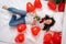 Excited Girl lying on bed red heart shape balloons with bouquet of flowers Woman rejoices gift on valentines day. Easy