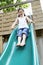 Excited Girl Playing On Slide In Park