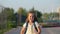 Excited girl with schoolbag runs to school past sports field