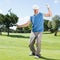 Excited golfer cheering on putting green