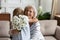 Excited grandmother embracing little granddaughter grateful for flowers on holiday
