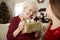 Excited Grandmother Receiving Christmas Gift From Granddaughter At Home