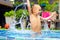 Excited happy kid boy jumping in pool, water fun