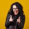 Excited happy woman in eyeglasses. Woman pointing fingers at camera, isolated on yellow. Close up portrait of hipster in glasses.