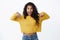 Excited happy young african-american cute female in yellow sweater gasping astonished pointing down, promote cool