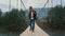 Excited hiker walk mountains on river bridge. Smiling man travel on holiday trip