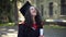 Excited intelligent beautiful woman kissing diploma standing at university campus in the morning. Portrait of smiling