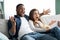 Excited interracial couple watching TV on couch at home