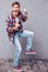 Excited joyful young man in checkered shirt and jeans dancing