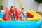 Excited kids, family having fun in colorful inflatable pool on patio