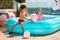 Excited kids having fun in inflatable pool on summer patio