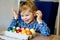 Excited little toddler girl coloring eggs for Easter. Child looking surprised at colored egg hoarding and celebrating