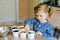 Excited little toddler girl coloring eggs for Easter. Cute happy child looking surprised at colorful colored eggs